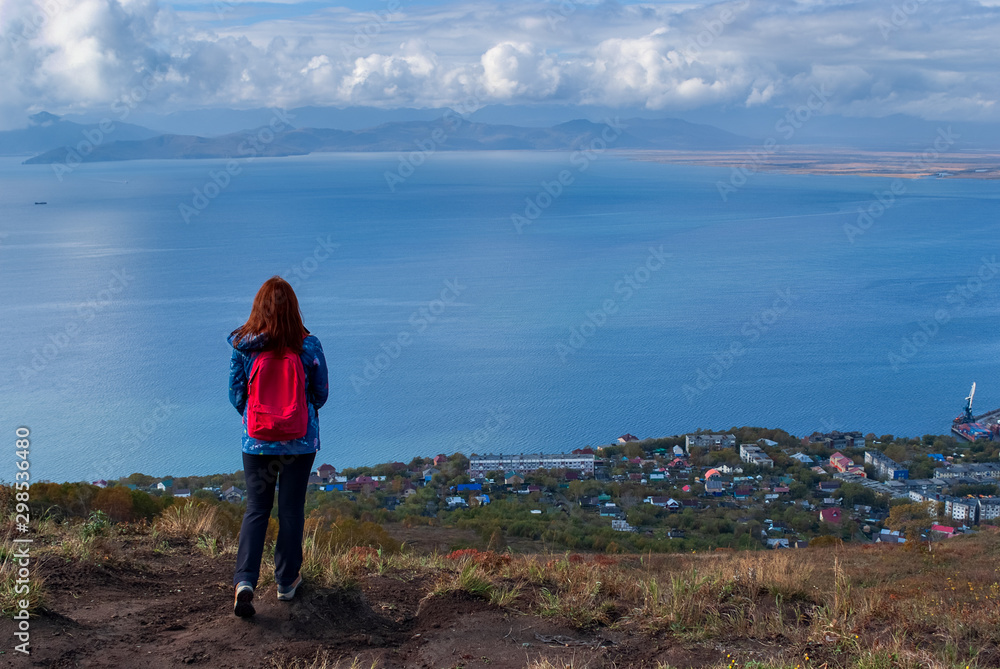 girl traveler on the edge of the cliff looking at the Bay and the ocean, the cold Pacific ocean, clouds