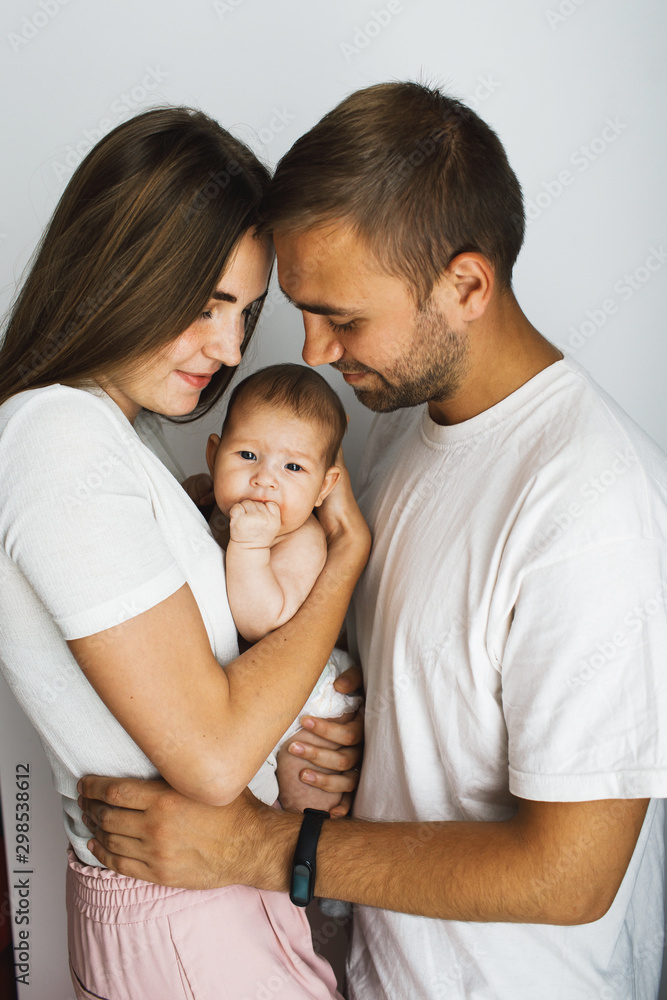 Happy young parents holding their baby and looking at her Happy young parents holding their baby and looking at her