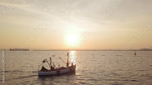 Fishing boat on the background of golden sunrise.  © MagioreStockStudio