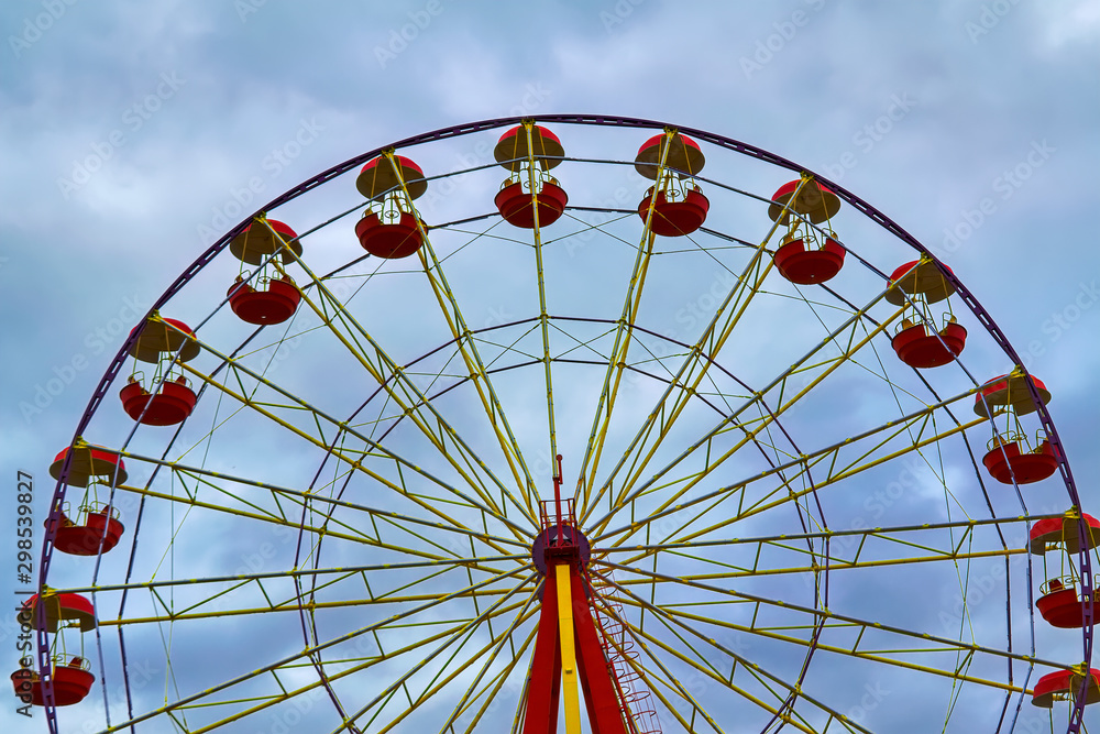 Ferris wheel on a background of cloudy autumn sky.