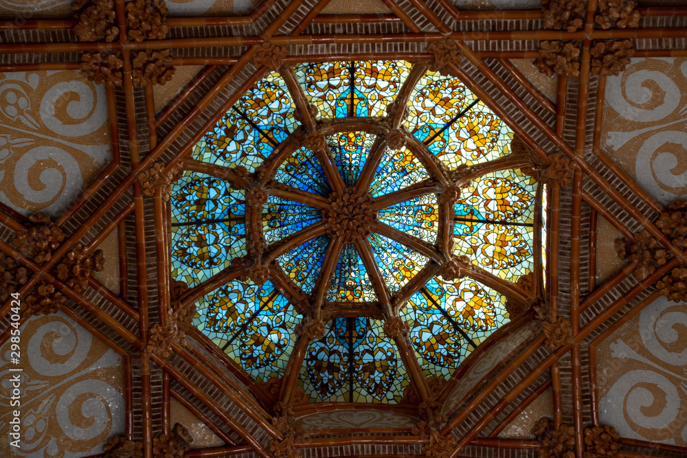 Looking up from the interior of the Modernista Sant Pau at the stained glass ceiling dome