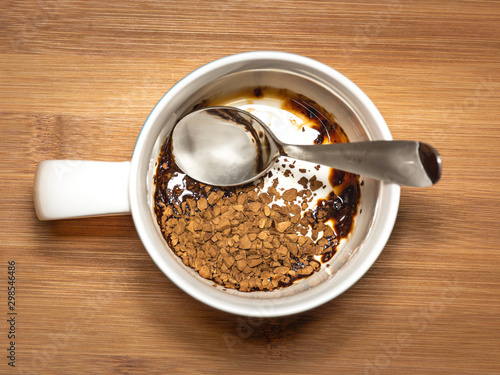 Instant Coffee in mug with spoon, freeze dried melting in bottom of cup. photo