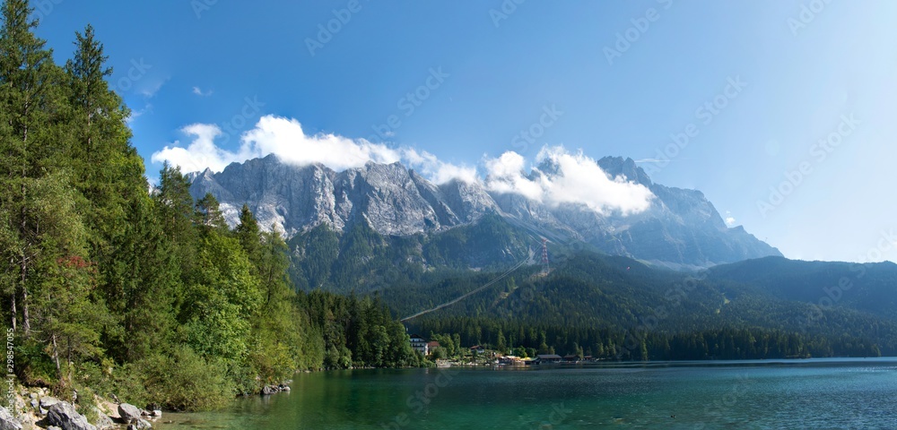 View of Lake Eibsee in Bavaria, Germany, with Forrest surrounding the lake and the Mountain in the back. 