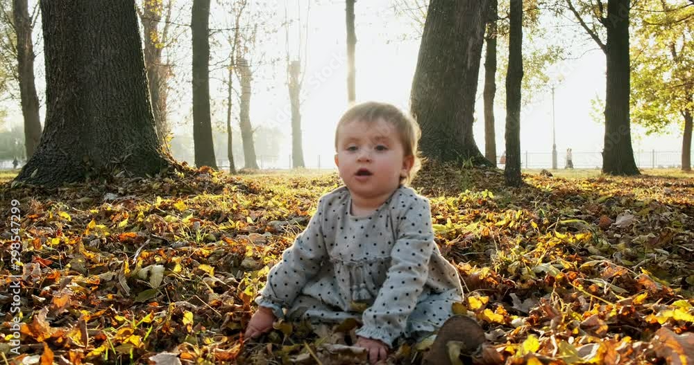 Little girl funny playing and throw up yellow leaves in the park at autumn fresh air Little girl funny playing and throw up yellow leaves in the park at autumn fresh air
