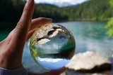 Hand holding crystal ball with reflection of Lake Eibsee