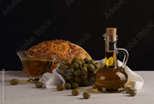 Still life with olive oil, olives and bread on a dark background