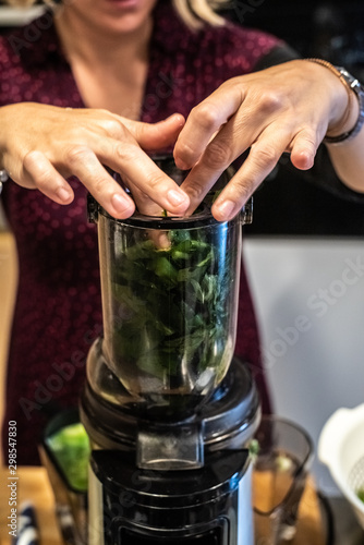 Woman preparing a healthy green juice in a blender.