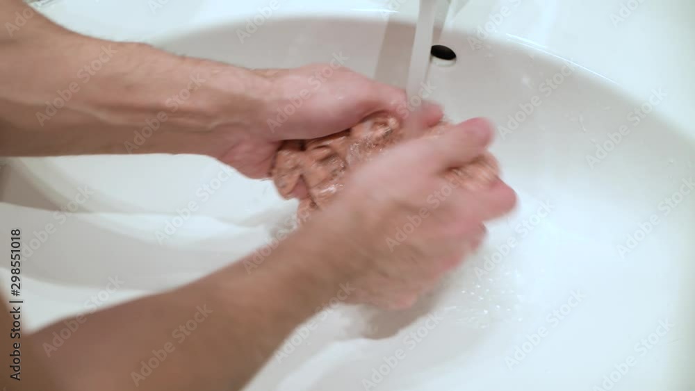 a man washes a children's shirt in the sink with his hands. Father is washing his little daughter's sweater a man washes a children's shirt in the sink with his hands. Father is washing his little daughter's sweater