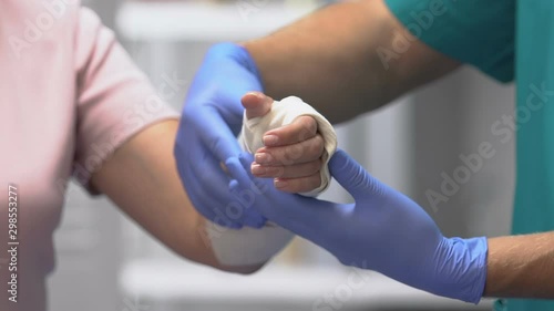 Doctor examining female patient arm in elastic bandage, joint injury, trauma