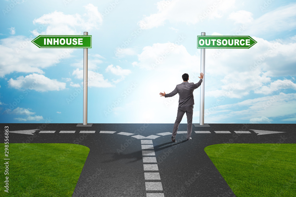 Businessman at crossroads deciding between outsourcing and inhou Businessman at crossroads deciding between outsourcing and inhou