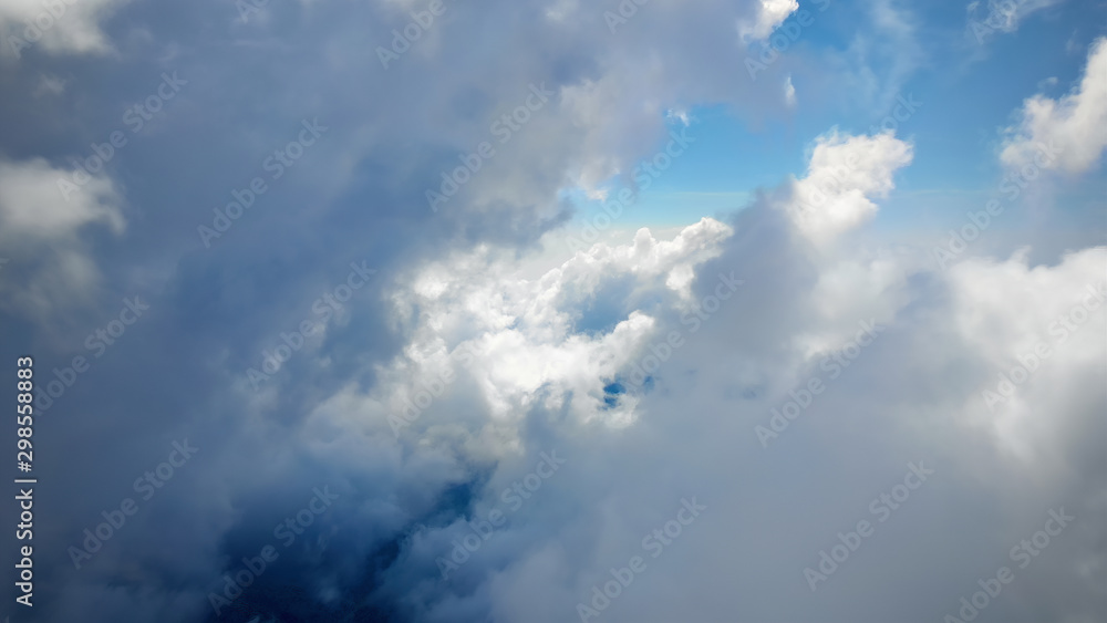 Obraz premium Flying through beautiful thick fluffy clouds. Amazing of soft white clouds moving slowly on the clear blue sky in pure daylight. Direct view from the cockpit.