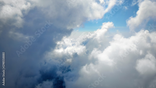 Flying through beautiful thick fluffy clouds. Amazing of soft white clouds moving slowly on the clear blue sky in pure daylight. Direct view from the cockpit.