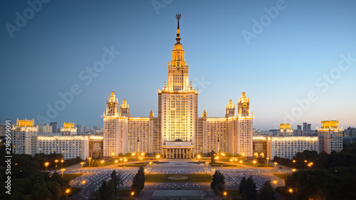 Motion of Moscow State University in the evening, aerial view. Camera moving towards MSU, showing also its alleys and outdoor lighting gradually turning on.