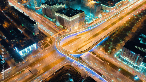 Beautiful motion of the big road junction on the night, view from above. Aerial shot of busy crossroad in Moscow center with a lot of traffic and glittering city lights.