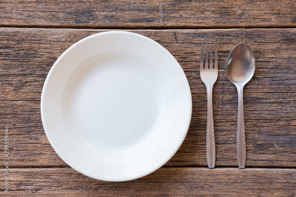 Top view of White dish and fork and spoon cutlery on a wooden background Top view of White dish and fork and spoon cutlery on a wooden background