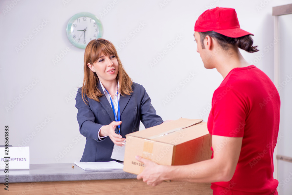Young male courier delivering box to hotel's reception Young male courier delivering box to hotel's reception