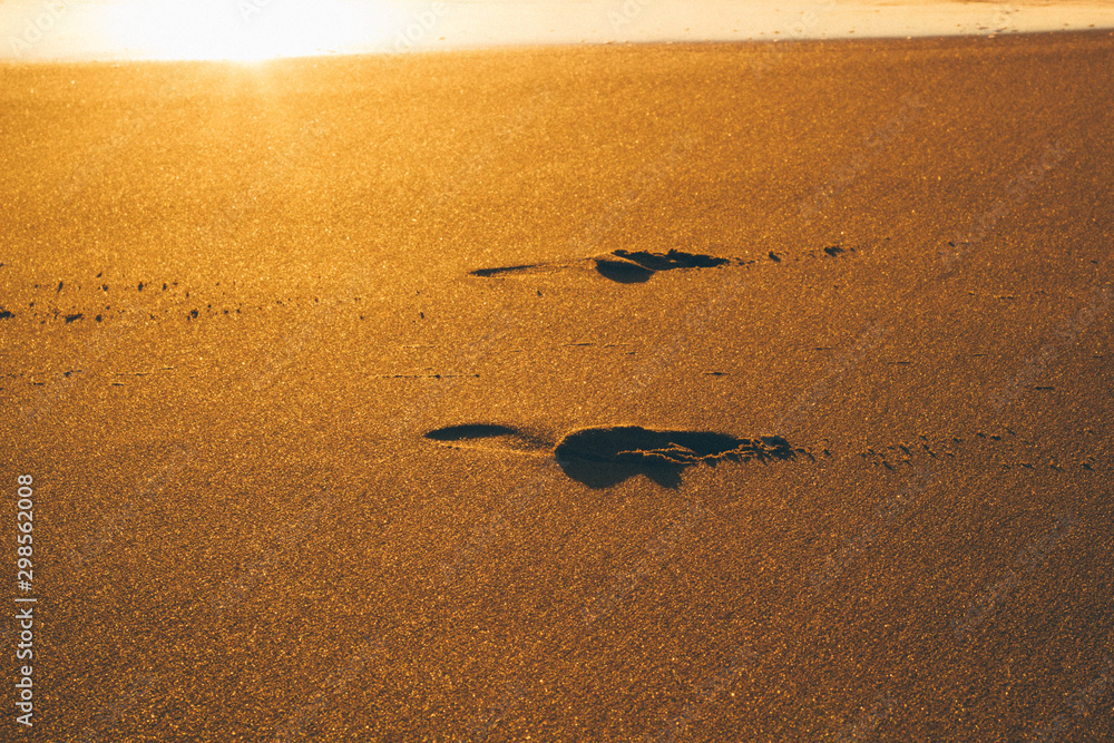 Obraz premium footprints in the sand at sunrise