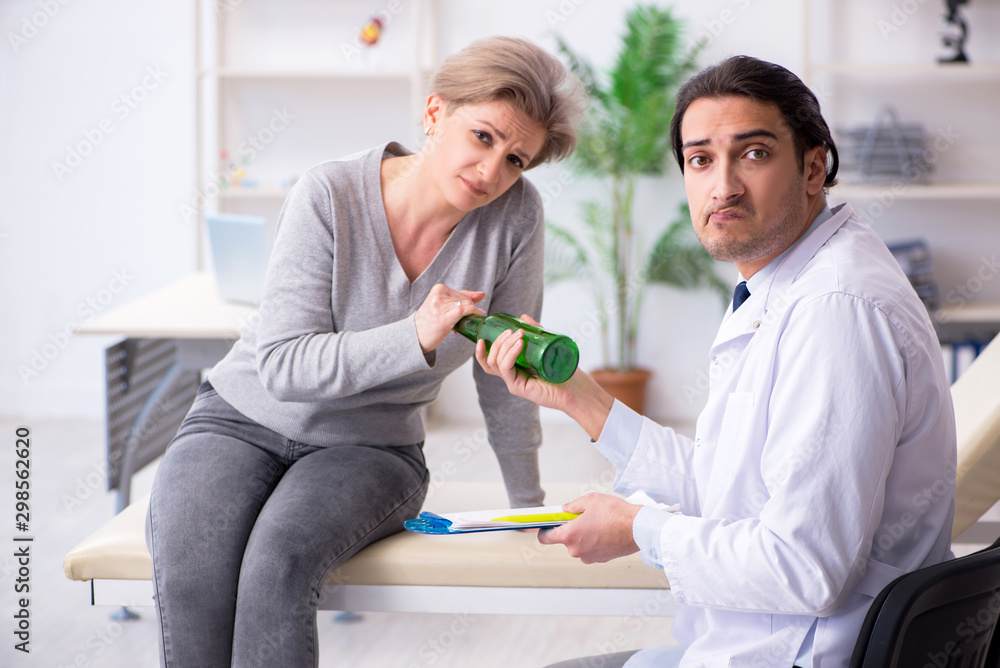 Fototapeta premium Female alcoholic visiting young male doctor