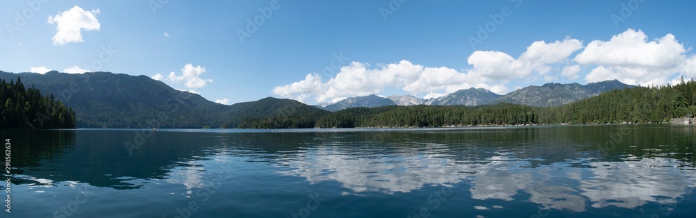 Wide angle view of with reflection of rolling mountains, blue sky, and clouds