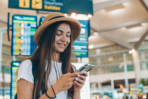 at the airport, a tourist reads a nice sms on the phone, with a smile