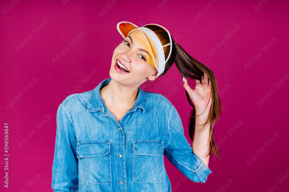 cheerful student in a visor fingering her hair with her hand. background pink cheerful student in a visor fingering her hair with her hand. background pink