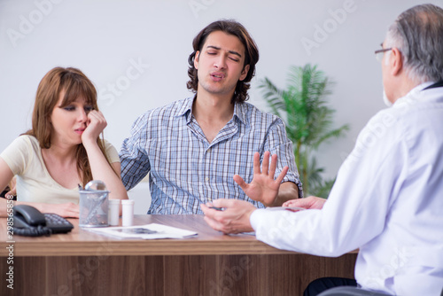 Young couple visiting old male doctor