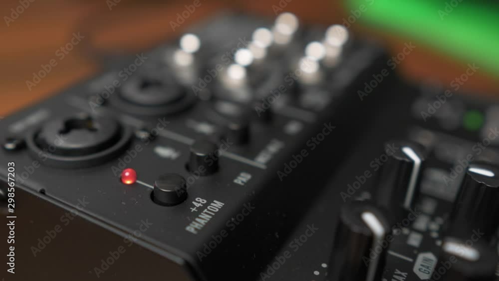 Close Up of index finger pushing phantom power button on dj mixer, Shallow Focus Close Up of index finger pushing phantom power button on dj mixer, Shallow Focus