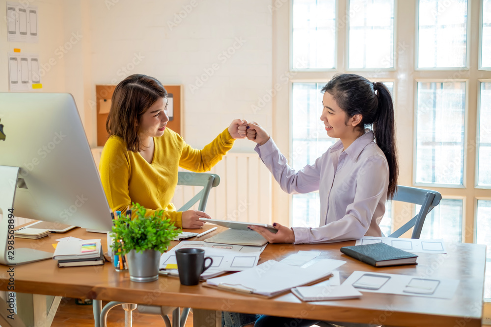 Two designer cheerful woman giving high five on the success of website design and application on mobile. Two designer cheerful woman giving high five on the success of website design and application on mobile.
