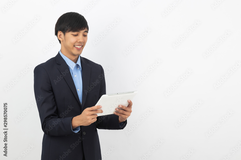 Young handsome asian business man playing and looking to tablet computer with smiling isolated on white background.