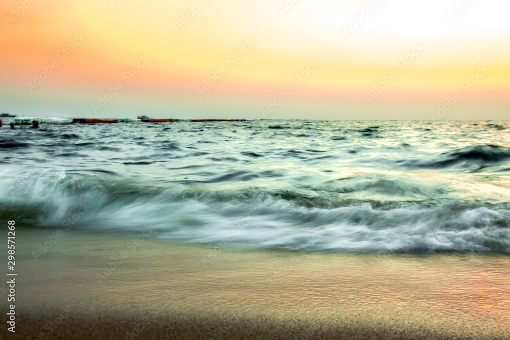 Soft and blur beautiful of ocean wave on sandy beach and sunset sky background at winter.