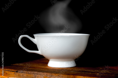 Hot coffee cup on old wooden table in dark background.