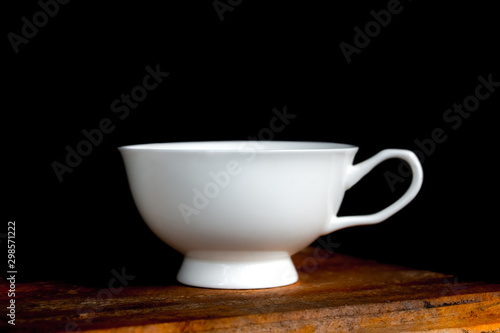 Coffee cup on old wooden table in dark background.
