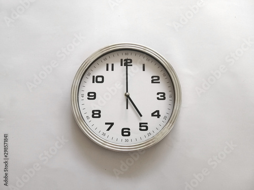 Wall clock isolated on a white wall, read at 5 o'clock. 5:00 pm, 5:00 am