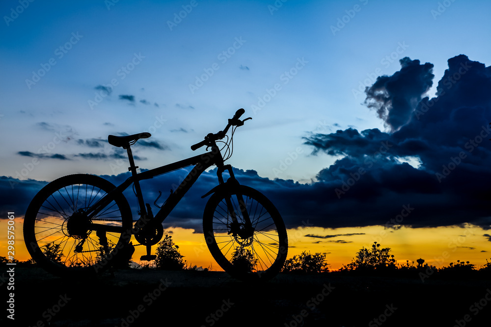 Obraz premium Silhouette of bicycle at the lake at sunset time in summer.