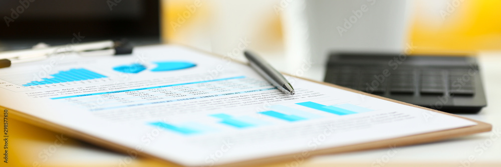 Fototapeta premium Silver pen lying on important stats paper clipped to pad