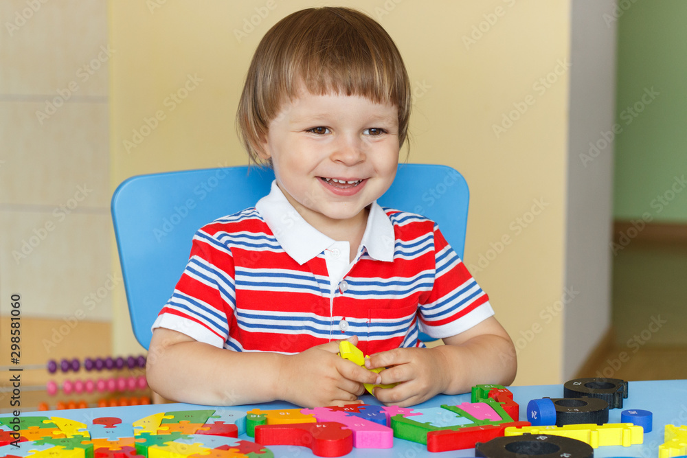 Happy smiling little baby boy playing with puzzle. Child development concept Happy smiling little baby boy playing with puzzle. Child development concept