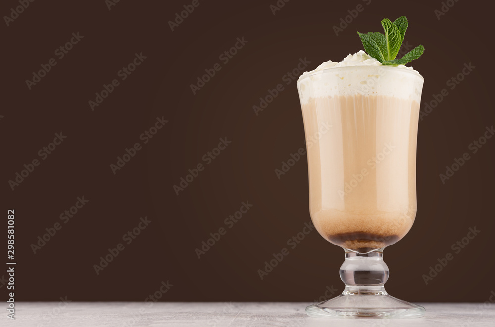 Irish coffee with cream, fresh mint in transparent glass on white wood board in brown color background, copy space. Irish coffee with cream, fresh mint in transparent glass on white wood board in brown color background, copy space.
