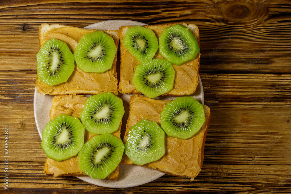 Tasty sandwiches with peanut butter and kiwi fruits on wooden table. Top view Tasty sandwiches with peanut butter and kiwi fruits on wooden table. Top view