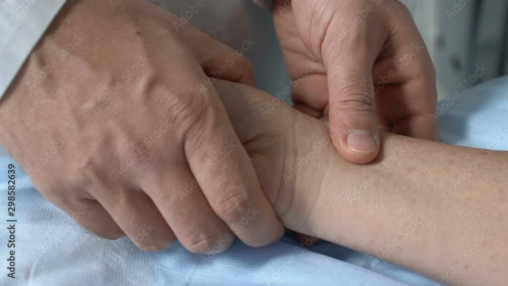 Doctor checking unconscious patient pulse touching wrist, first aid in hospital Doctor checking unconscious patient pulse touching wrist, first aid in hospital