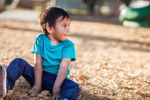 Картината върху платно Latino boy with dirty hands from playing with woodchips from a playground all by himself and looking away