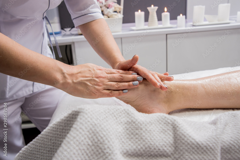 Beautiful young woman enjoying foot massage in spa salon. Cosmetology