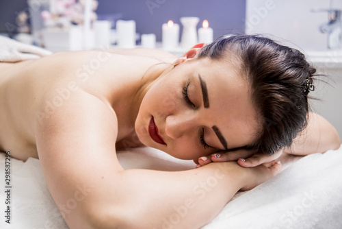 Beautiful young woman enjoying massage in spa salon. Cosmetology