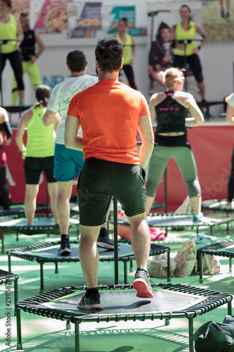 Mini Rebounder Workout - People doing Fitness Exercise in Class at Gym with Music and Teacher on Stage