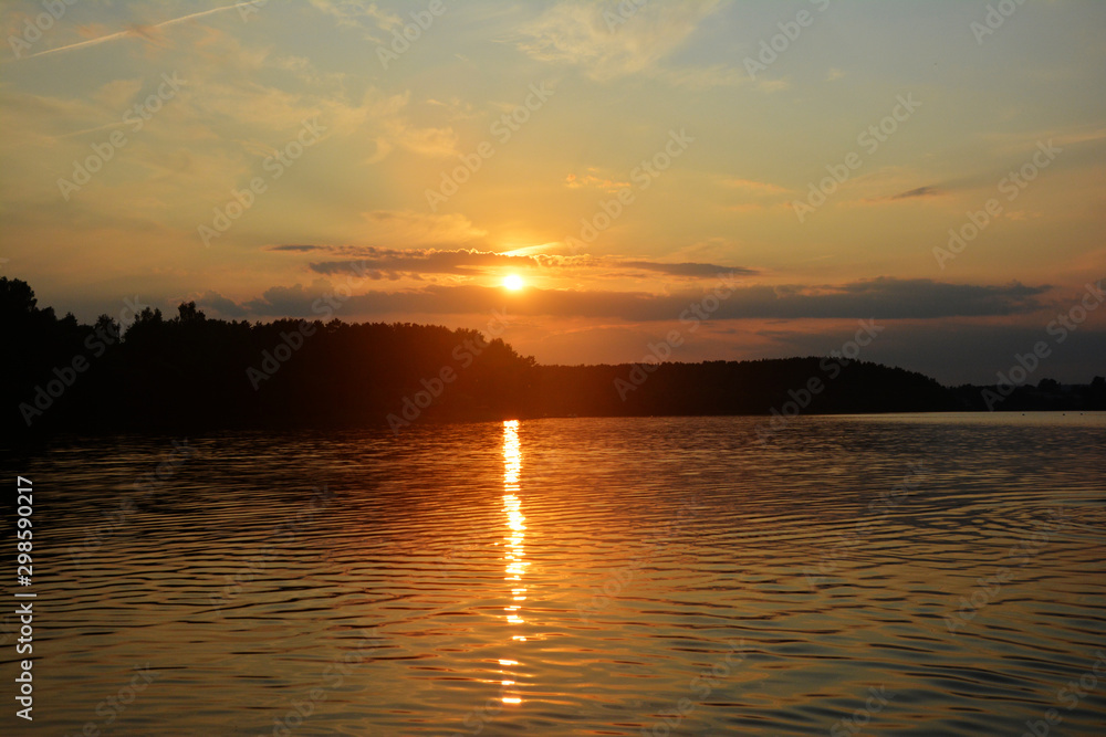 Beautiful Sunset orange lake landscape. The sun's rays are reflected in the water.