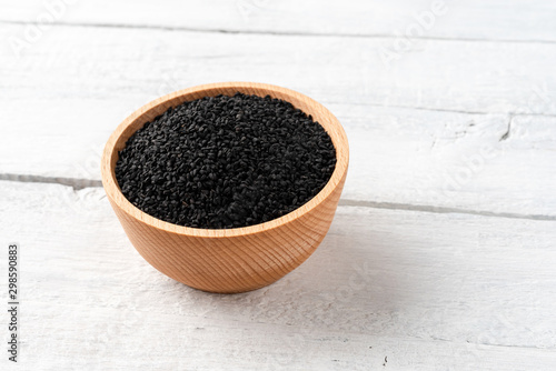 Black cumin seeds in bowl on vintage wooden background