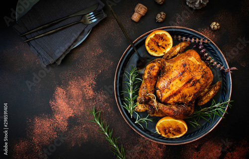 Baked whole chicken with oranges and rosemary. Tray with a festive Christmas dish on a dark rustic background. Top view, flat lay. Copyspace