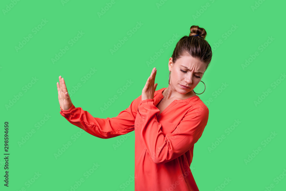 Side view portrait of dissatisfied woman with bun hairstyle in red blouse turning way with disgust, frowning showing stop gesture with both hands. indoor studio shot isolated on green background Side view portrait of dissatisfied woman with bun hairstyle in red blouse turning way with disgust, frowning showing stop gesture with both hands. indoor studio shot isolated on green background