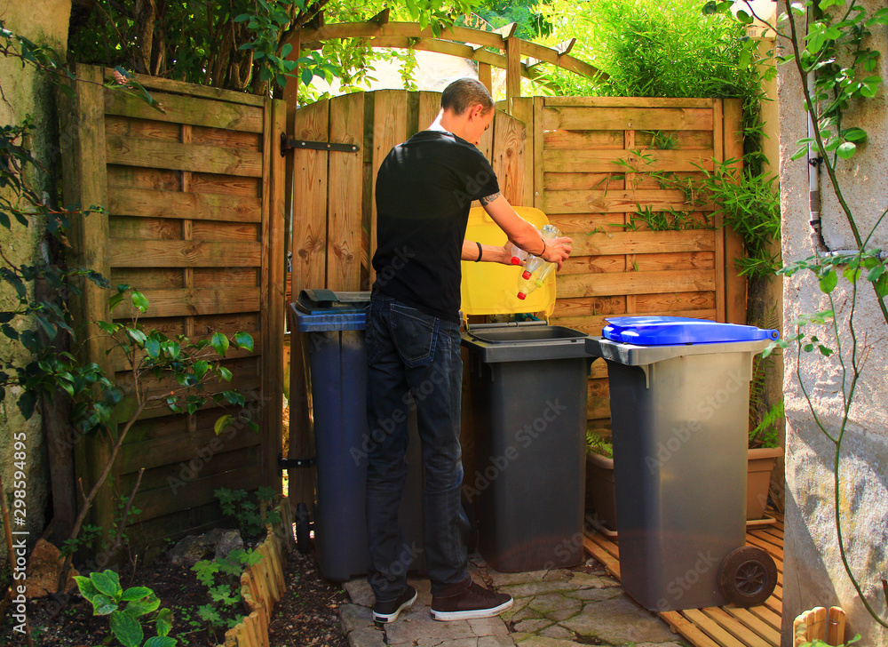 Person making a selective sorting of waste. Man putting plastic bottles in a yellow bin for recycling. Person making a selective sorting of waste. Man putting plastic bottles in a yellow bin for recycling.