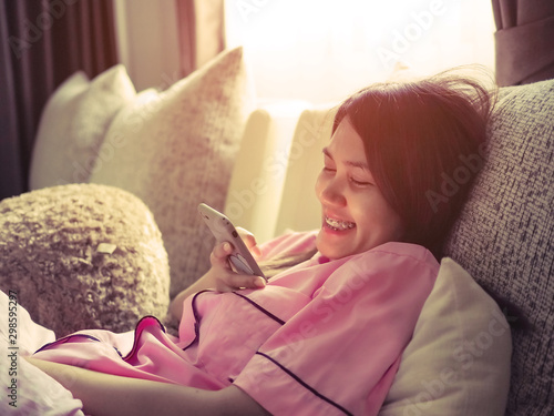 woman reading electornic book in smartphone on sofa at home photo