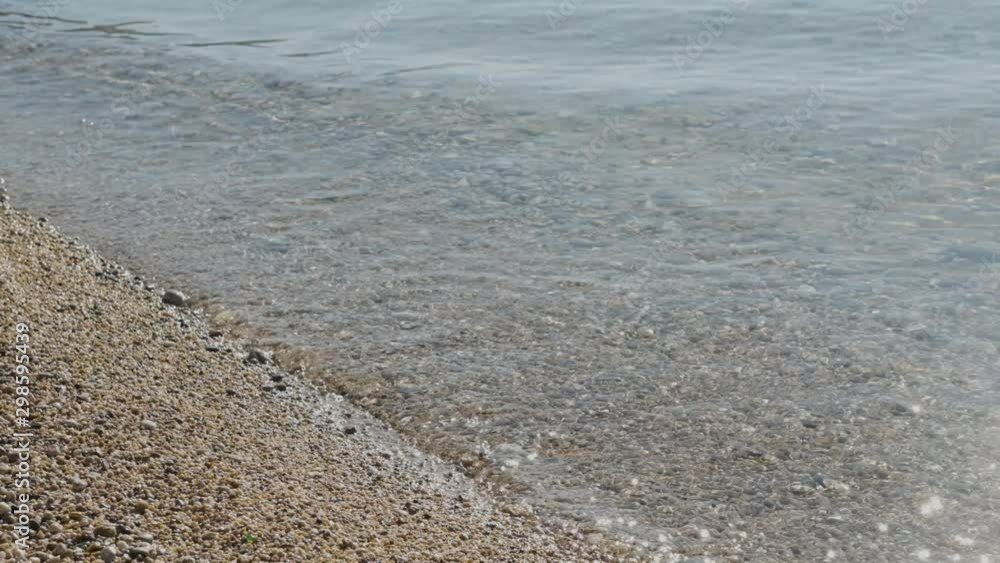 Sea water surface at the pebble beach. Beautiful sun beams in ripple waves. Sea water surface at the pebble beach. Beautiful sun beams in ripple waves.